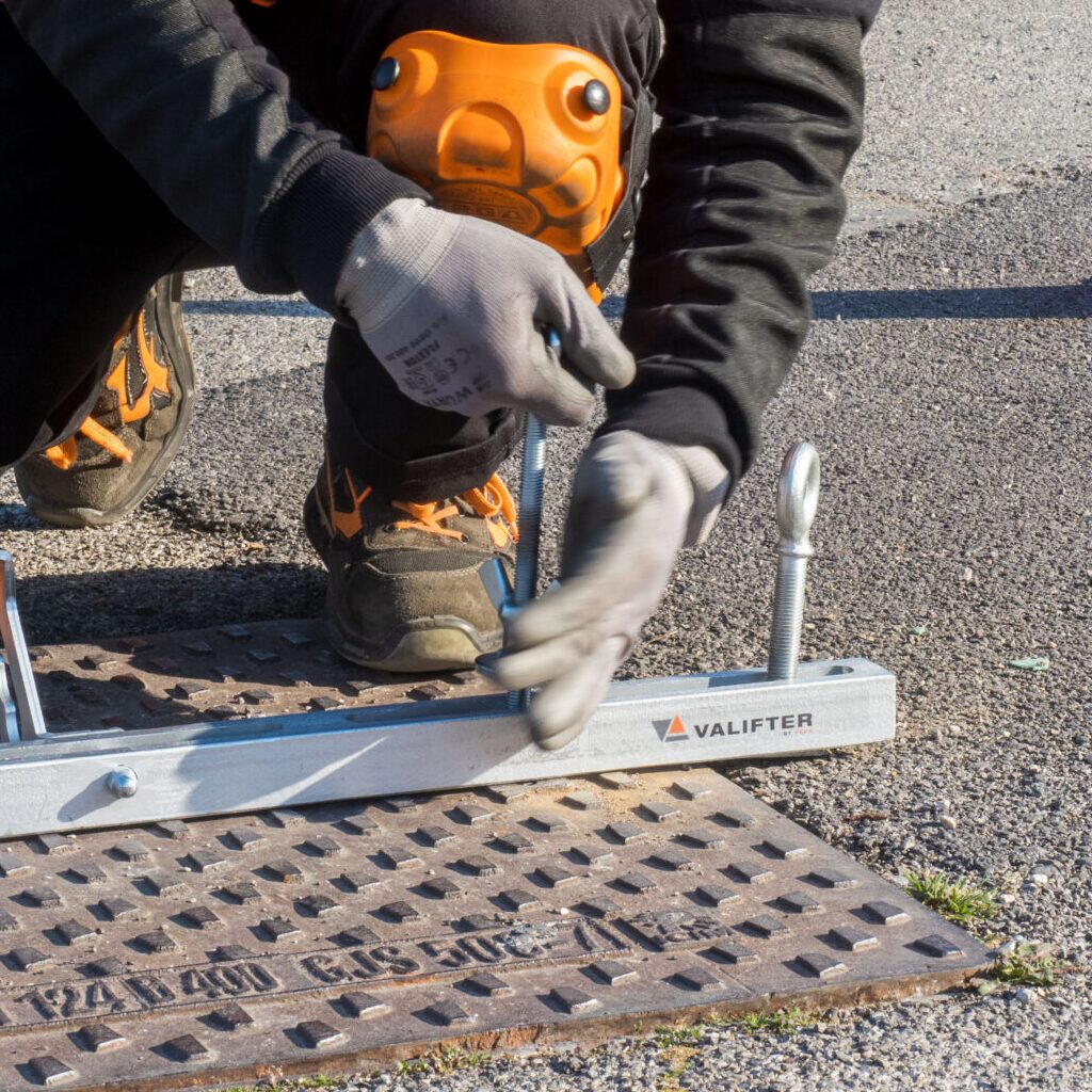 Operatore che utilizza un sistema di aggancio e sblocco Valifter su un chiusino stradale